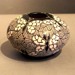 Sgraffito butterfly and geometric design on a black and white jar