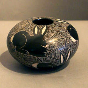 Sgraffito rabbit and mesh design on a black and white jar
