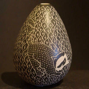 Sgraffito raccoons, cats and geometric design on a black and beige jar