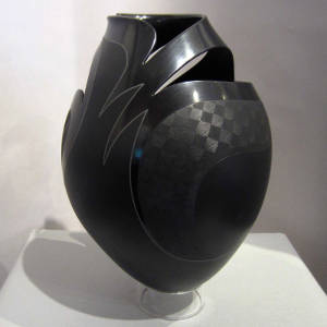 Sgraffito fine line and geometric designs on a black and gray on black jar with cutouts