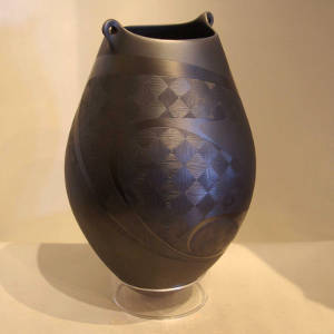 Sgraffito geometric design on a black on black jar