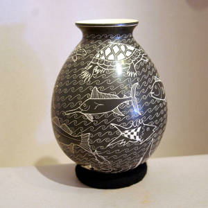 Sgraffito fish and water designs decorate a black and white jar