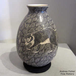 Sgraffito raccoon and geometric design on a black and beige jar