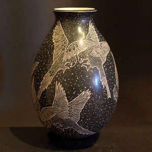 Sgraffito parrot and background design on a black and beige jar