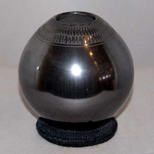 A necklace of black matte geometric design on a polished black graphite jar