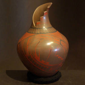 Red and black paquime designs on a brown jar with an organic kiva step opening
