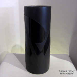 A sgraffito and painted geometric design on a black on black on black cylinder