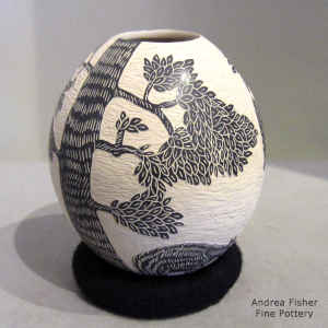 A sgraffito wildlife and nature design on a black and white jar