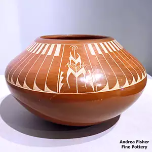 A sgraffito corn plant and feather design on a red bowl