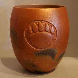 Carved bear paw imprint and fire clouds on an orange micaceous jar