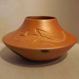 Carved lizard design on a golden micaceous jar