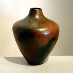 Narrow neck and pine pitch coating on a polished brown jar with fire clouds