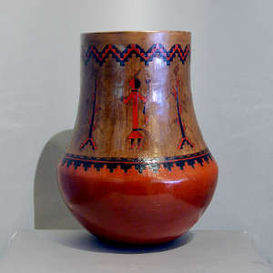 Yei figures and Navajo carpet design on a tall brown jar
