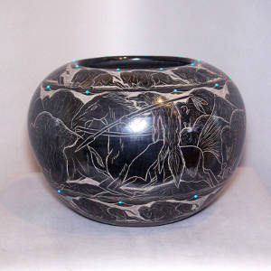 Sgraffito buffalo hunt scene and inlaid turquoise accents on a black jar