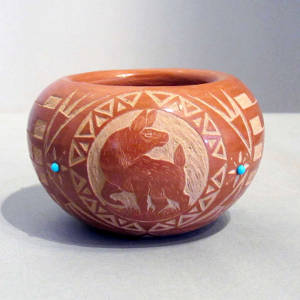 Sgraffito animal and geometric design on a red bowl with inlaid turquoise accents