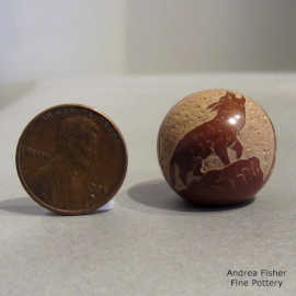 Miniature red seed pot decorated with a sgraffito wolf, geometric design and an inlaid stone