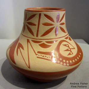 An avanyu and geometric design on a brown on red jar
