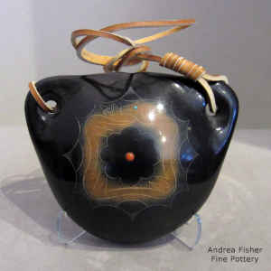 Black canteen with a sienna spot, a sgraffito avanyu design and an inlaid stone