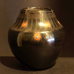 Inlaid stones and a feather and spider design on a black jar