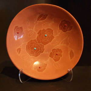 Sgraffito floral design with inlaid turquoise and coral on a red plate