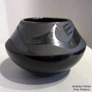 An avanyu design on a black on black jar