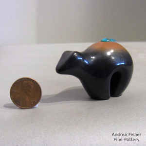 An inlaid turquoise on the back of a two-tone miniature bear figure