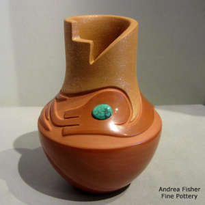 An avanyu design carved into a red jar with a kiva step rim, inlaid turquoise and micaceous slip