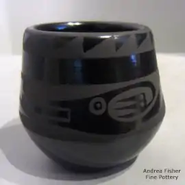 An avanyu and geometric design on a small black-on-black jar