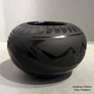An avanyu and geometric design on a black on black jar