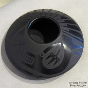 An avanyu and feather design on a black on black jar