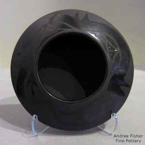 An avanyu design on a black on black jar