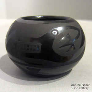 An avanyu design on a black on black jar