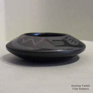 An avanyu and geometric design on a black on black bowl