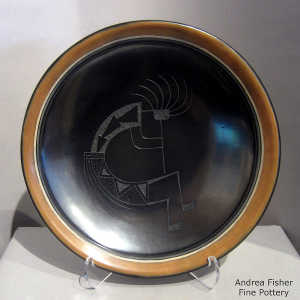 Sgraffito kokopelli design on a black plate with a sienna rim