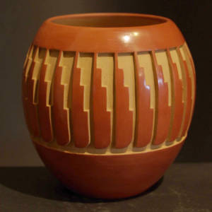 Feather design carved into a polished red jar