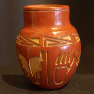 Bear Paw and geometric designs carved into a polished red jar
