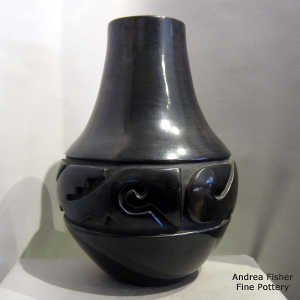 An avanyu design carved into a tall black jar