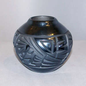 Kokopelli and geometric design carved into a black on black jar
