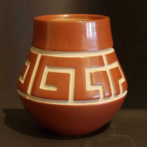 Geometric design carved into a polished red jar