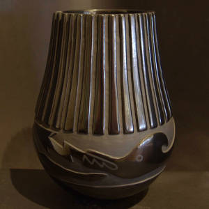 Ribs and an avanyu design carved into a tall black jar