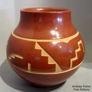 A stylized avanyu design carved into a red jar