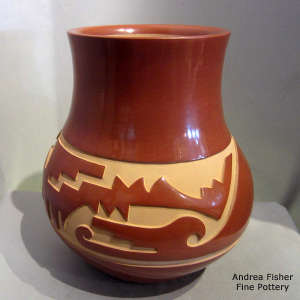 An avanyu design carved into a red jar
