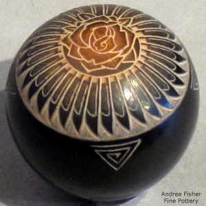 Sgraffito flower, feather and geometric design on a black seed pot with a sienna spot