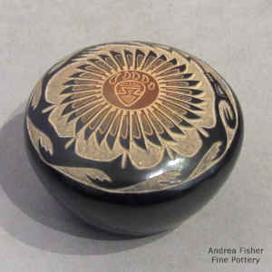Sgraffito feather, bear paw, avanyu and geometric design on a black seed pot with a sienna spot