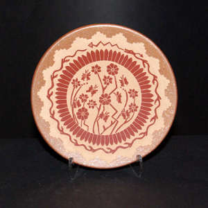 Sgraffito butterfly, avanyu and floral design on a red plate with a micaceous rim