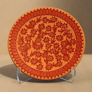 Sgraffito hummingbird, flower and geometric design on a red plate