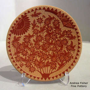 Sgraffito hummingbird, sunface, floral and geometric design on a red plate