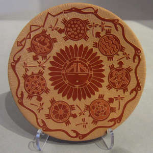 Sgraffito turtle, sun-face and geometric design on a red plate