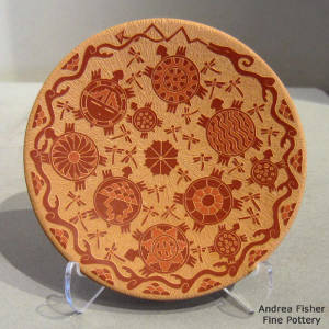 Sgraffito turtle, dragonfly, avanyu and water design on a red plate