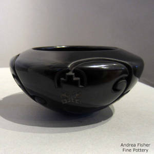 Geometric designs carved into a black bowl with sgraffito butterflies